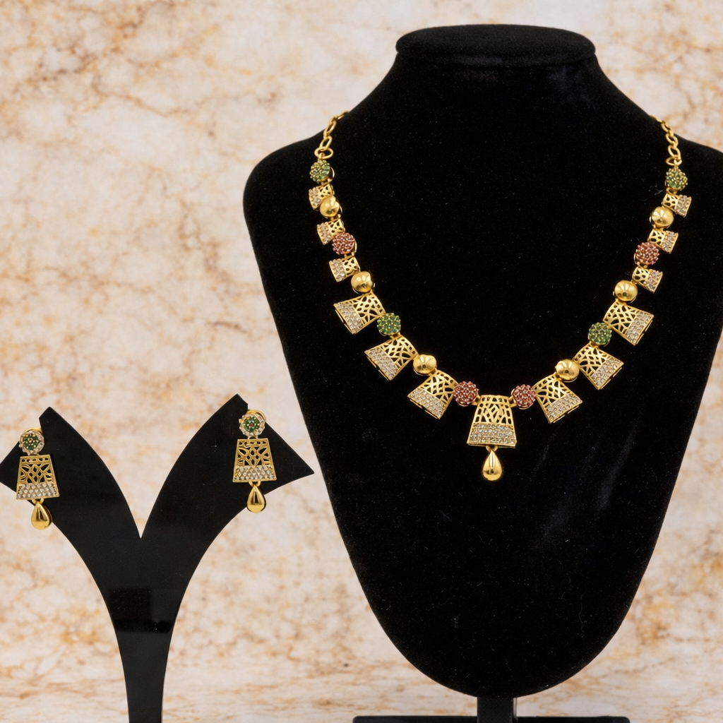 Gold necklace and earrings on a black stand with a beige marble background