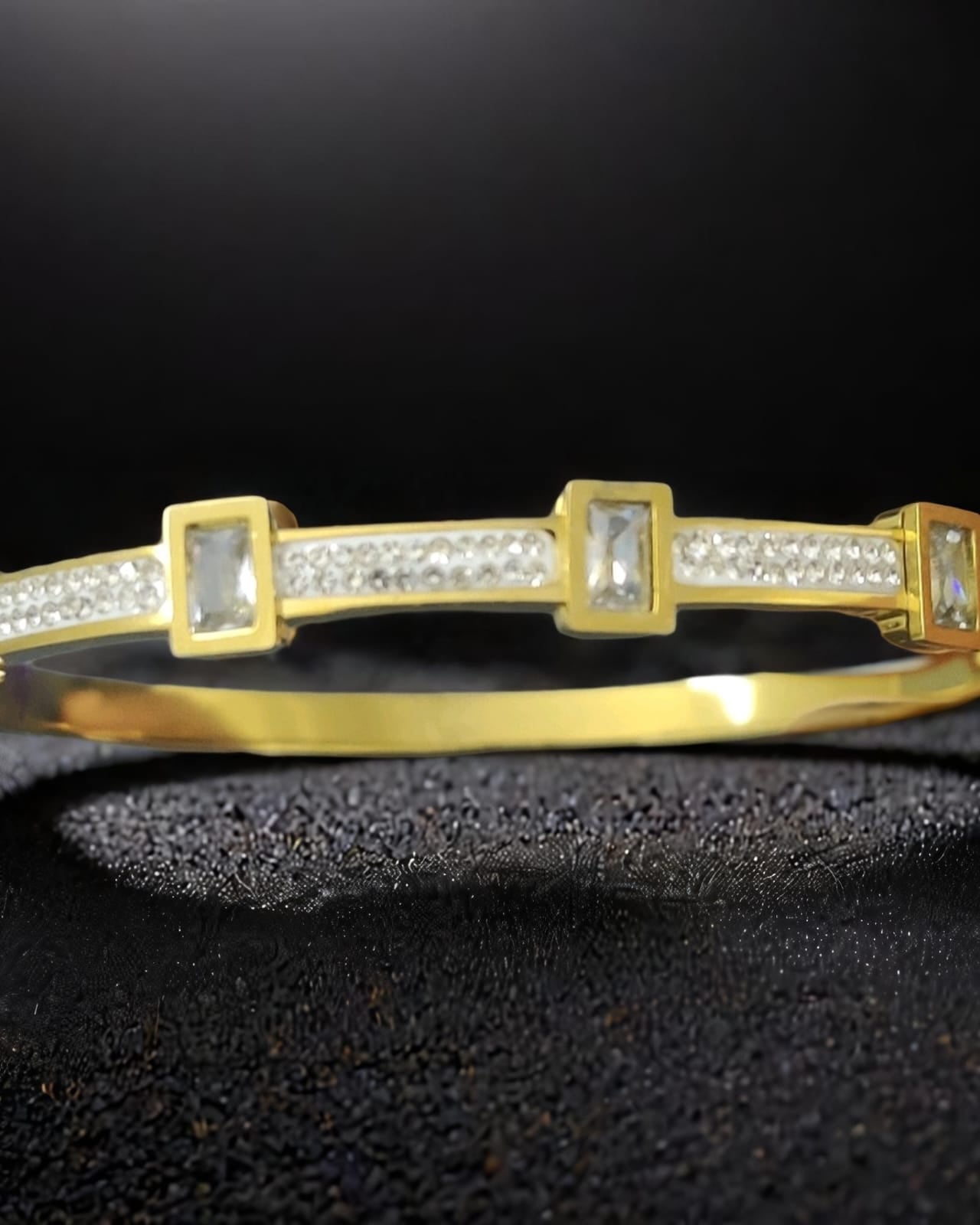 Gina CZ Stone Bracelet – gold stainless steel bangle with baguette CZ stone settings and pavé crystal detail, close-up on dark background – GemofU