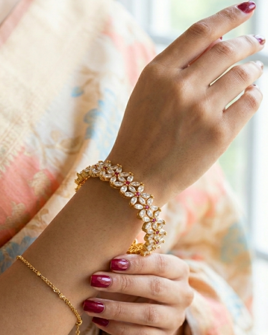 Close-up of a hand wearing a gold bracelet with a blurred background