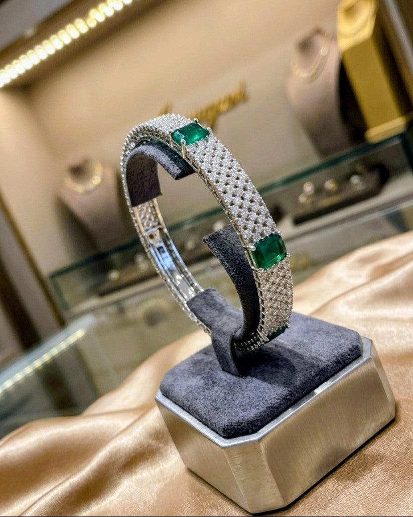 Silver bracelet with green gemstones on a display stand in a jewellery store.