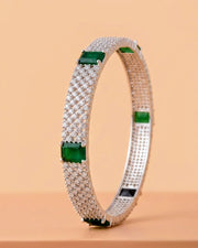 Silver bracelet with green gemstones on a beige background