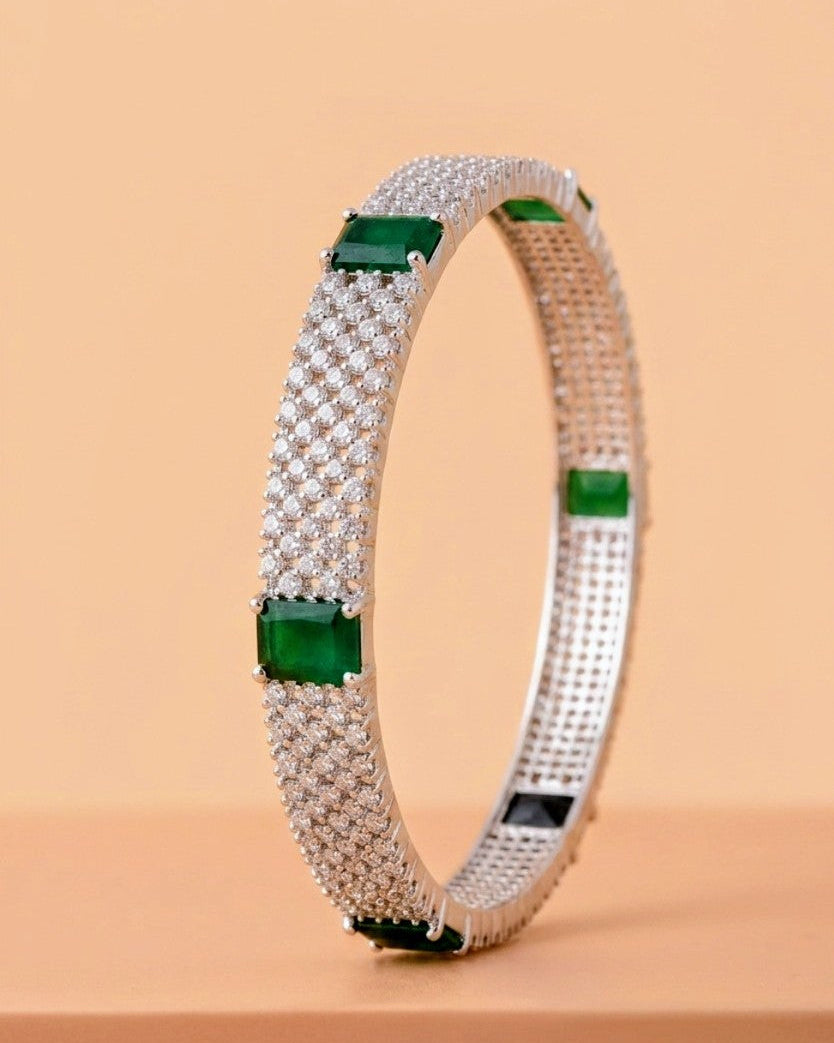 Silver bracelet with green gemstones on a beige background