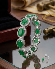 Green gemstone bracelet with silver accents on a reflective surface