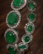 Bracelet with green gemstones and silver accents on a wooden surface