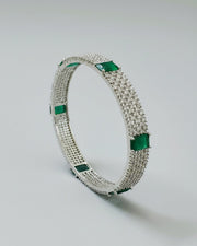 Silver bracelet with green gemstones on a light gray background
