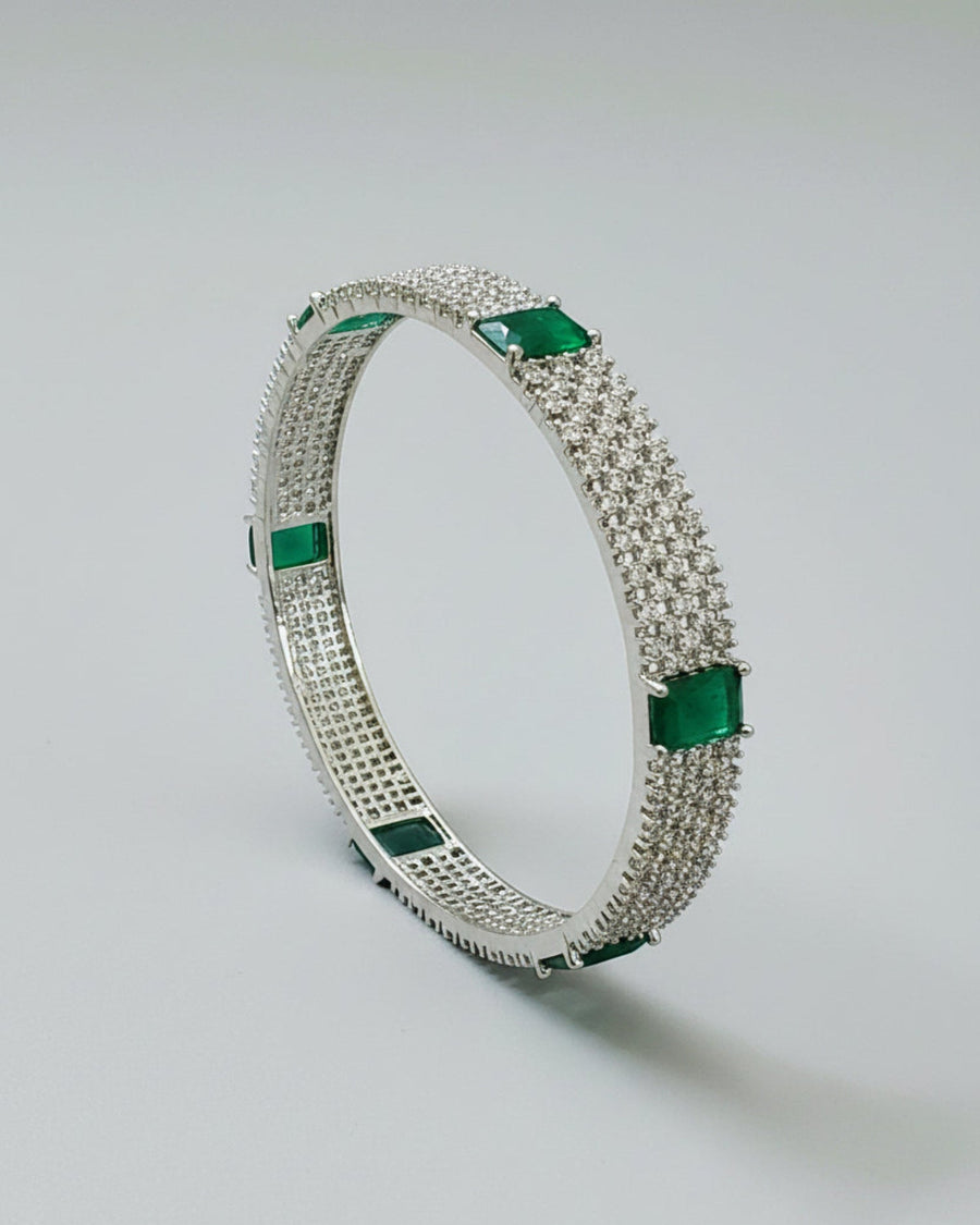 Silver bracelet with green gemstones on a light gray background