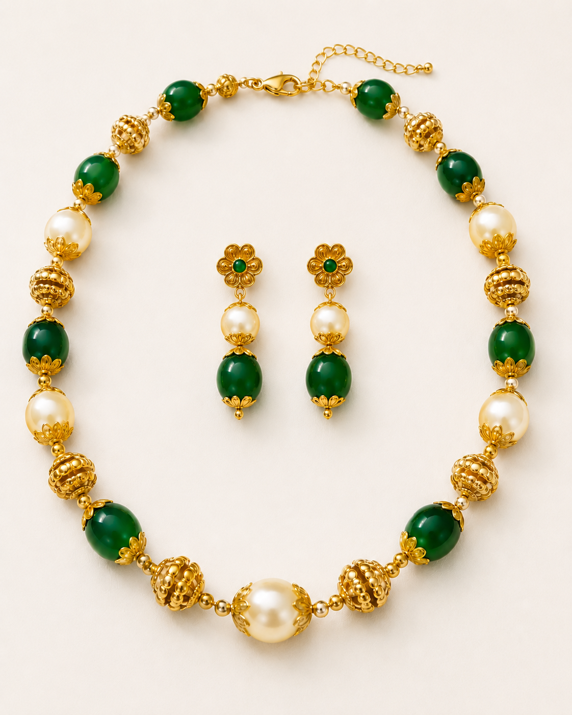 Gold, green, and pearl jewelry set on a white background
