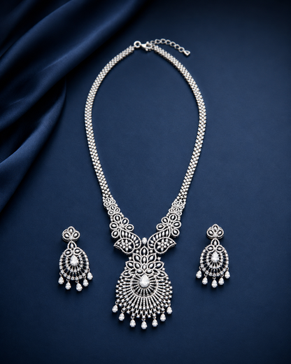 Silver necklace and earrings set on a dark blue fabric background