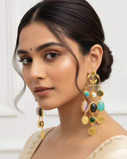 A pair of ornate gold dangle earrings displayed on a black velvet jewelry bust. The earrings feature multiple colorful gemstone drops including turquoise, white pearls, pink, green, and dark gray stones, set against a plain white background.