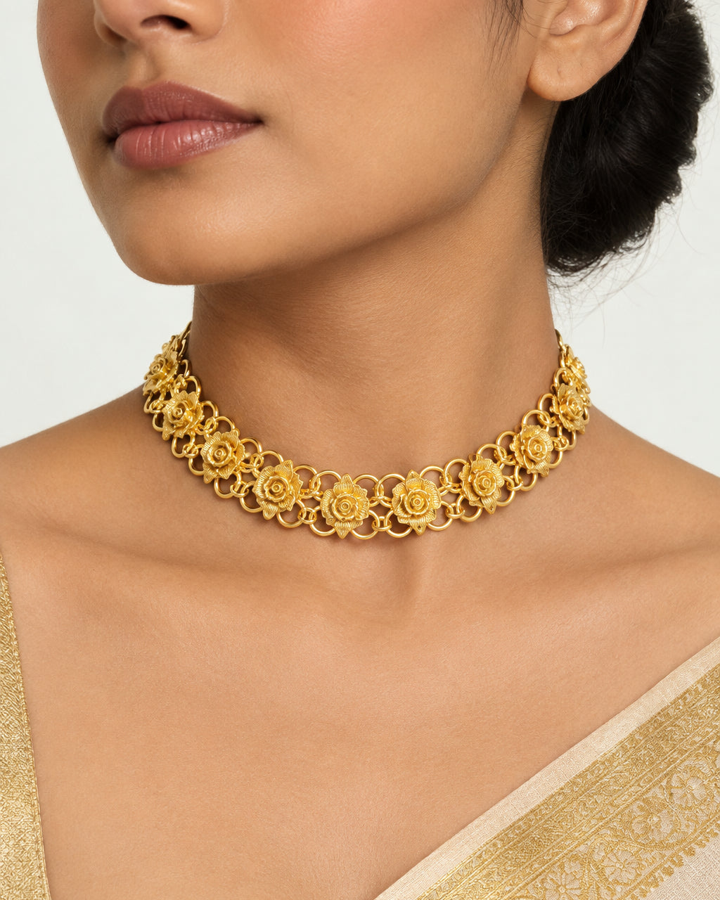 A gold-tone floral link chain necklace displayed on a black velvet jewelry bust against a light gray background.
