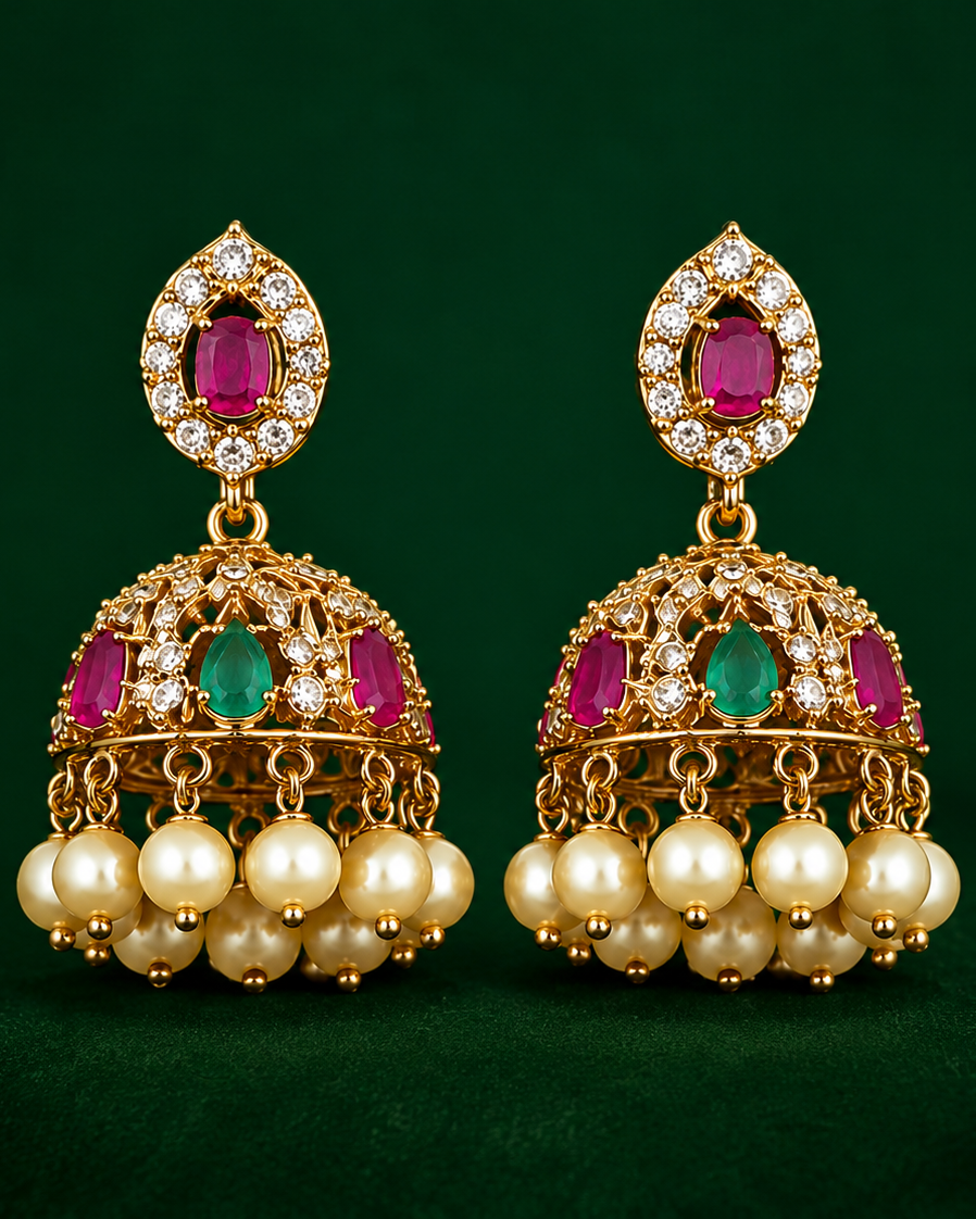 Gold earrings with red and green gemstones on a green background