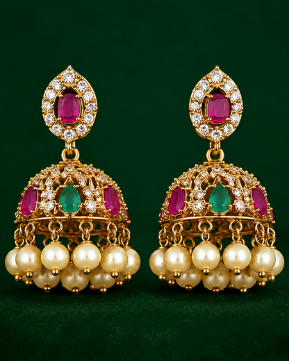 Gold earrings with red and green gemstones on a green background