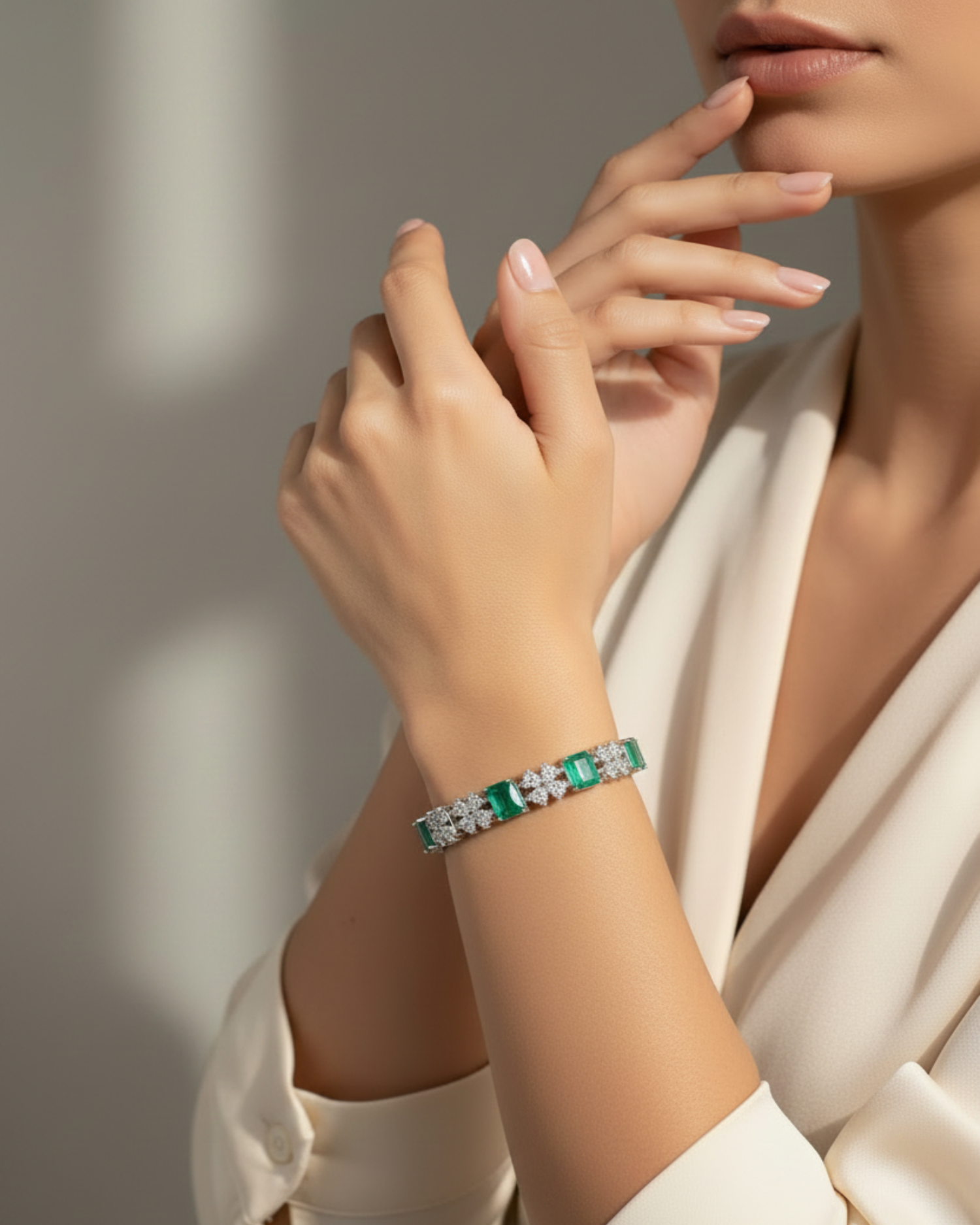 A close-up lifestyle shot of a model wearing a green and white beaded bracelet on her wrist, paired with a cream-colored satin blouse against a softly lit neutral background.