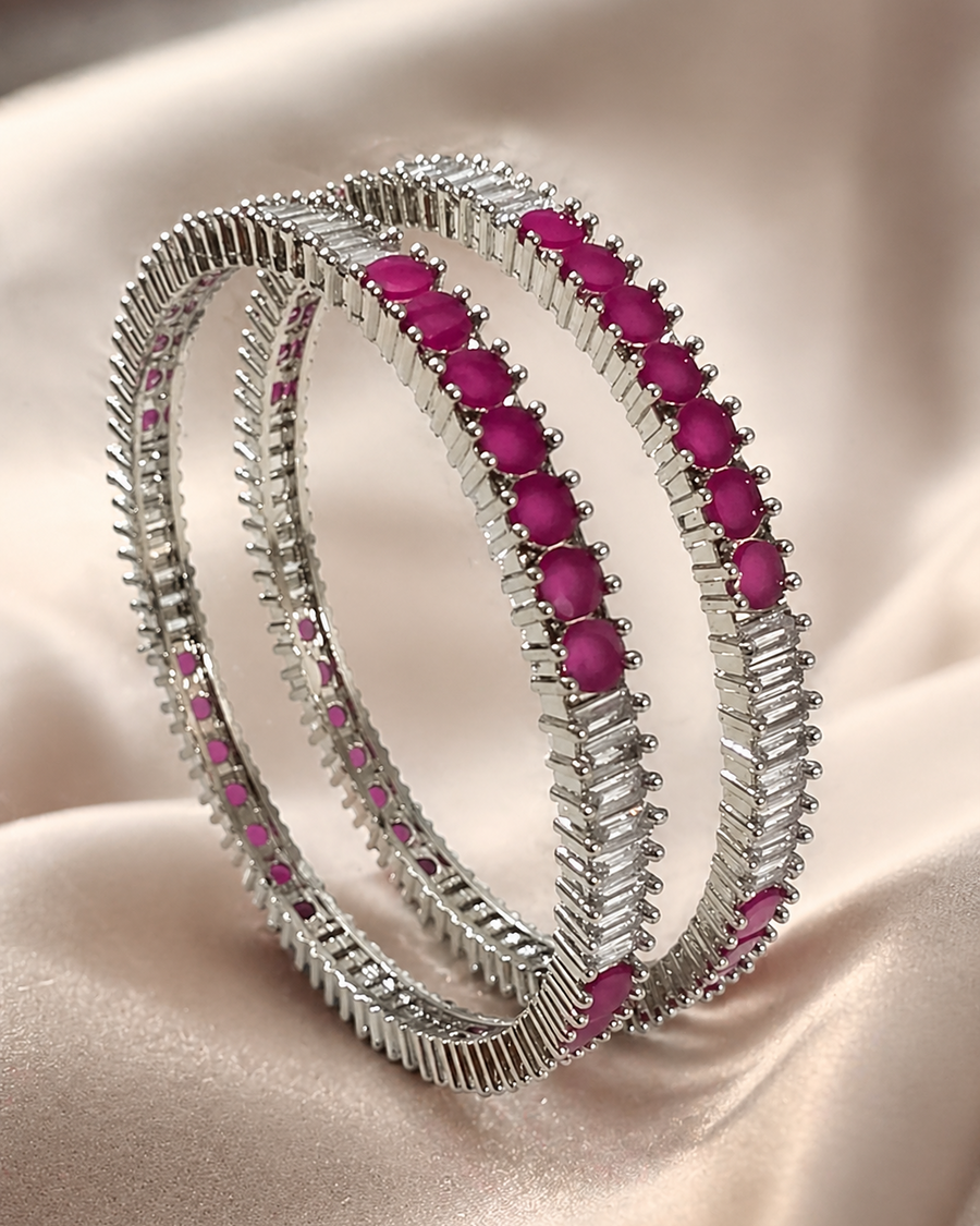Two silver-toned bangles with textured, ridged edges and rows of oval pink gemstones