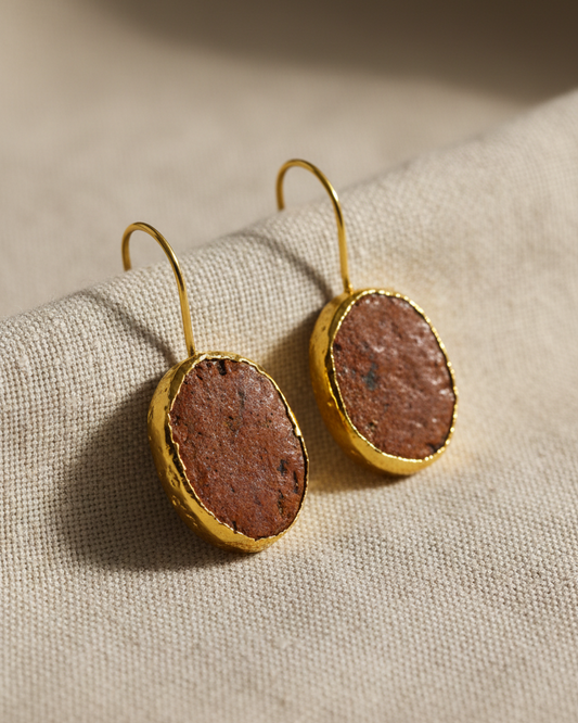 GemofU   Gold-tone drop earrings with oval brown textured stone pendants, displayed on a beige background