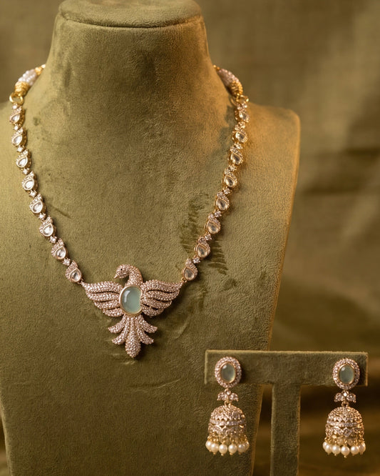 Swan Designer CZ Necklace – gold-tone CZ swan pendant necklace with aqua stone centre and oval CZ chain, with jhumikki earrings on olive bust – GemofU
